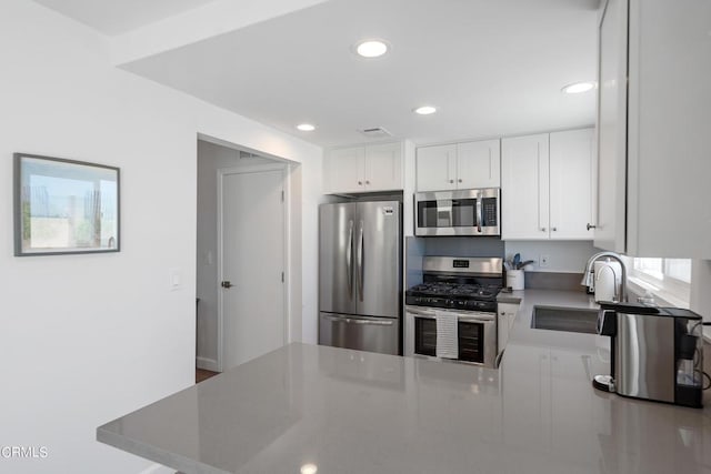 kitchen featuring a sink, stainless steel appliances, a peninsula, and white cabinets