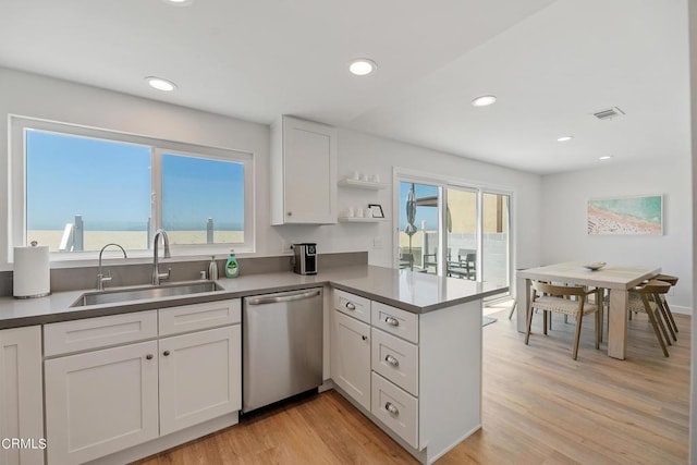 kitchen with a sink, white cabinetry, light wood-style floors, a peninsula, and dishwasher