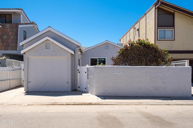 view of front of home with a garage, driveway, a fenced front yard, and stucco siding