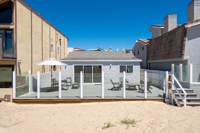 rear view of property featuring stucco siding, a patio, and fence