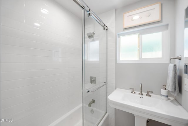 full bath with a sink and shower / bath combination with glass door