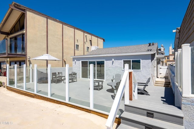 back of property featuring stucco siding, a deck, and fence