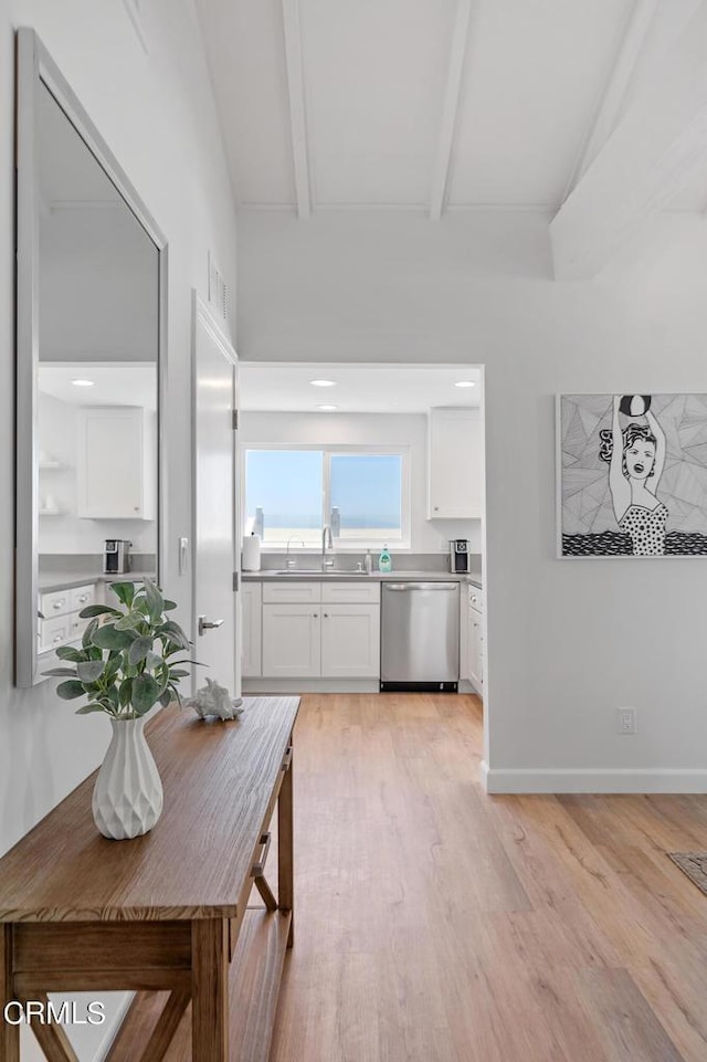 kitchen with baseboards, white cabinetry, a sink, dishwasher, and light wood-type flooring