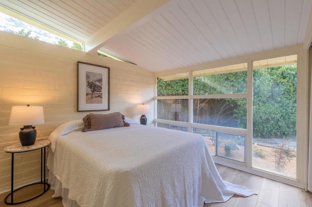 bedroom featuring lofted ceiling with beams and light hardwood / wood-style floors