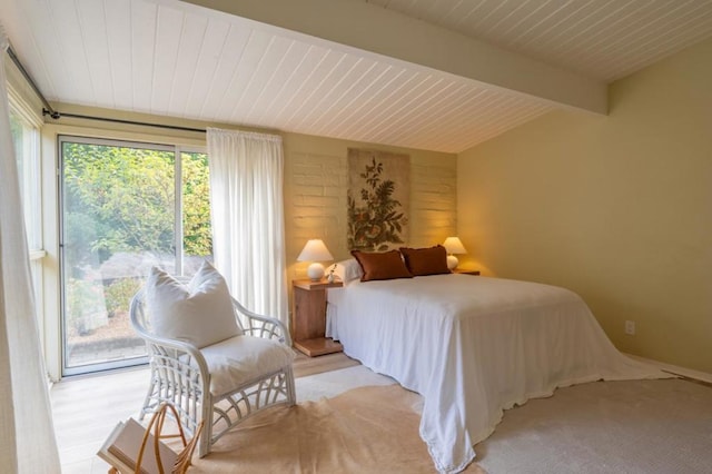 bedroom with beamed ceiling and access to outside