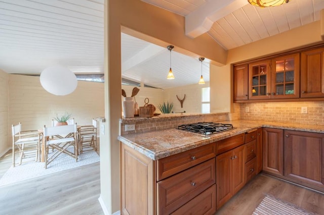 kitchen featuring pendant lighting, backsplash, light hardwood / wood-style floors, and stainless steel gas stovetop