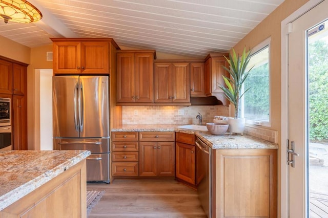 kitchen featuring lofted ceiling with beams, sink, light hardwood / wood-style flooring, decorative backsplash, and appliances with stainless steel finishes