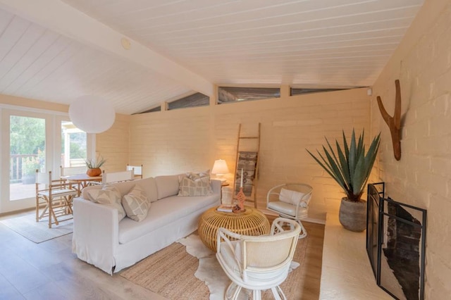 living room featuring wood-type flooring, lofted ceiling with beams, and brick wall