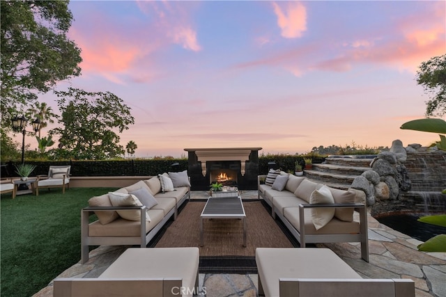 patio terrace at dusk featuring an outdoor living space with a fireplace