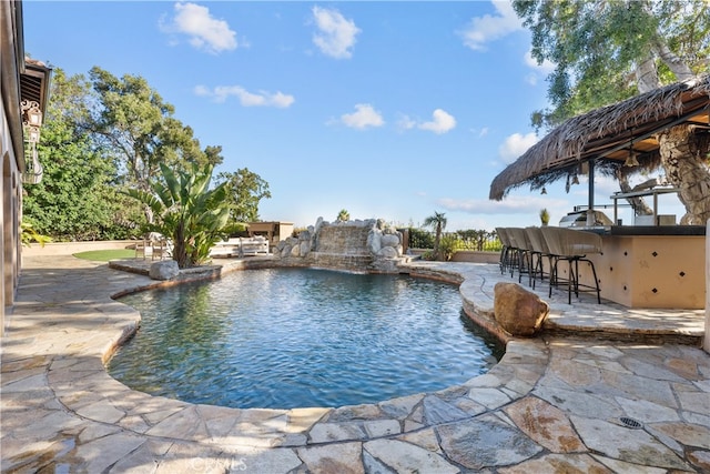 view of swimming pool featuring pool water feature, a patio, and an outdoor bar