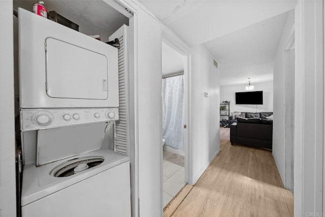 laundry area featuring laundry area, light wood-style flooring, and stacked washer / drying machine