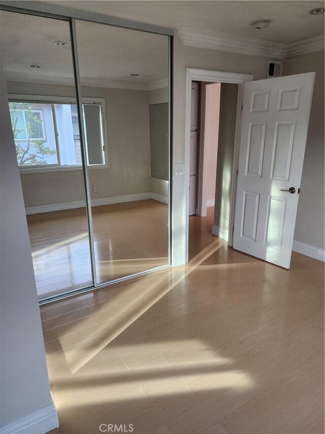 unfurnished bedroom with baseboards, wood finished floors, and crown molding