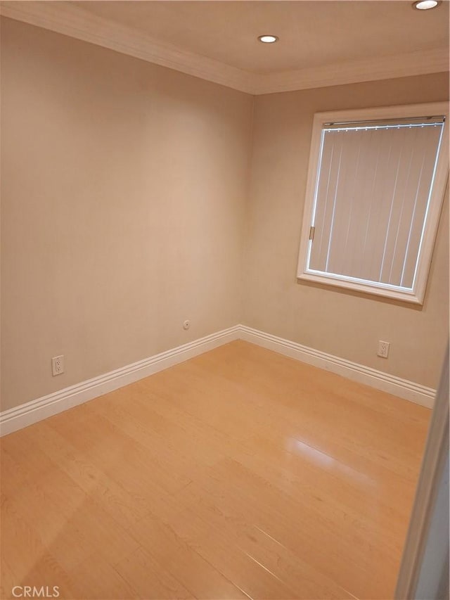 empty room featuring baseboards, recessed lighting, wood finished floors, and crown molding