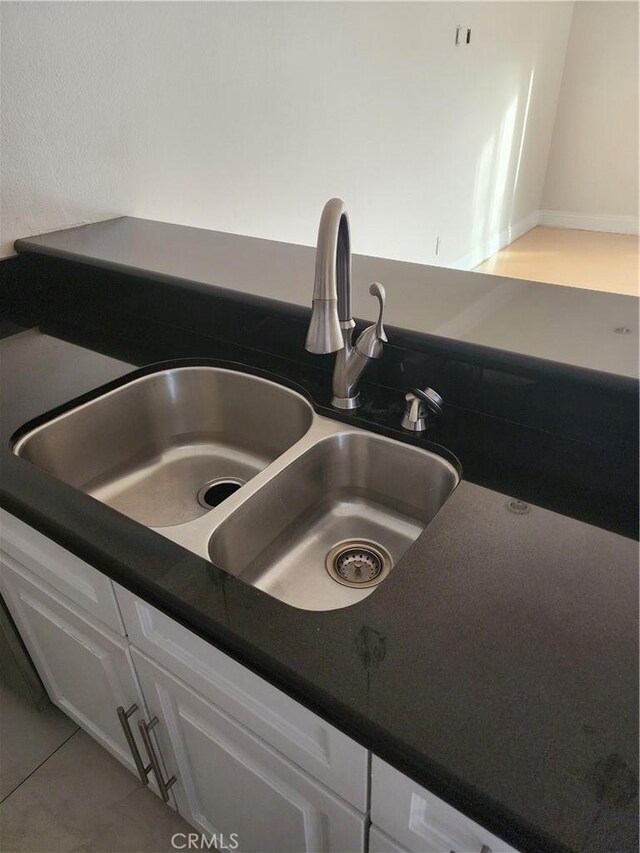 details with dark countertops, white cabinets, and a sink