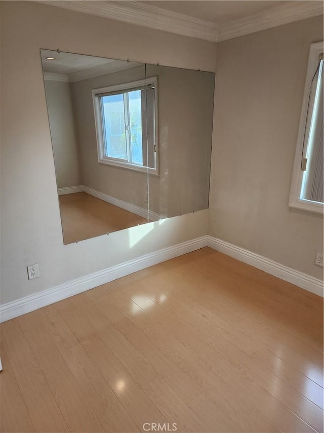 spare room with baseboards, wood finished floors, and crown molding