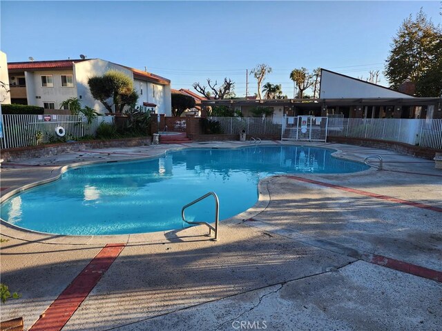 pool with a patio and fence