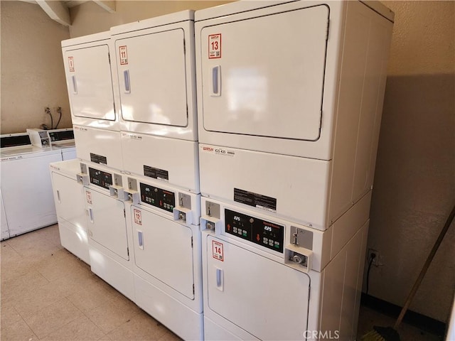 community laundry room with stacked washer and dryer, washer and dryer, and light floors