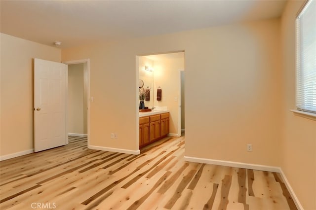 unfurnished bedroom with connected bathroom and light hardwood / wood-style flooring