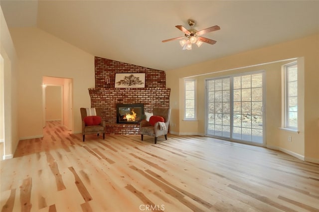 living area with a brick fireplace, ceiling fan, light wood-type flooring, and vaulted ceiling