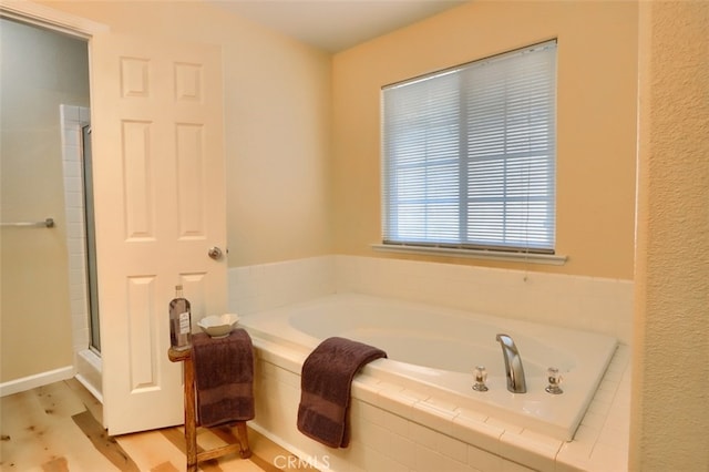 bathroom featuring tiled bath and hardwood / wood-style flooring