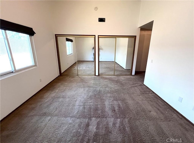 unfurnished bedroom featuring carpet flooring, multiple closets, and a high ceiling