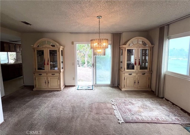 unfurnished dining area with a notable chandelier, plenty of natural light, light colored carpet, and a textured ceiling