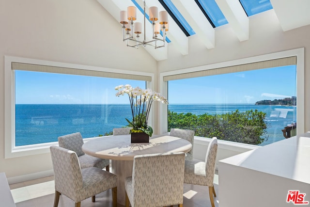 dining area with a water view, beam ceiling, a skylight, and an inviting chandelier