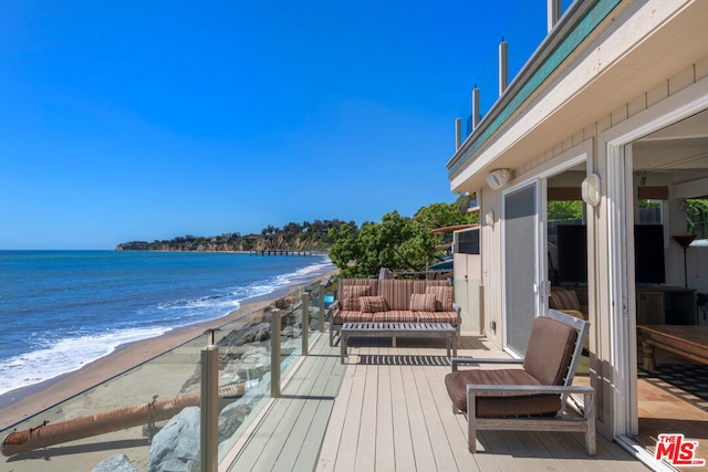 wooden deck with a water view and a view of the beach