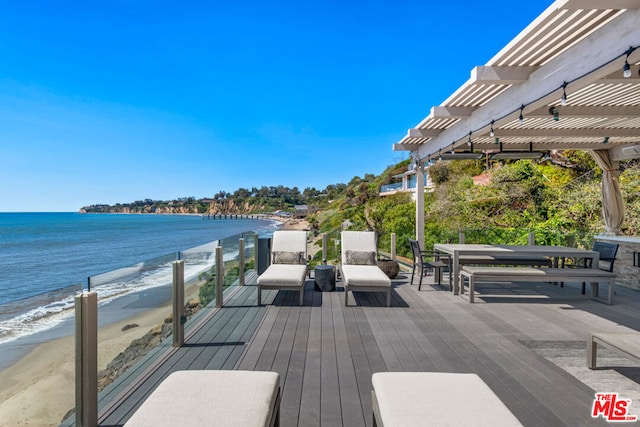 wooden terrace with a view of the beach, a water view, and a pergola