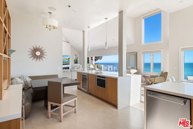 kitchen featuring wine cooler, stainless steel appliances, sink, decorative light fixtures, and a water view