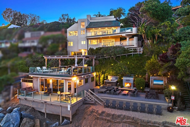 back house at dusk featuring a patio and a balcony