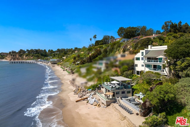 birds eye view of property with a water view and a beach view