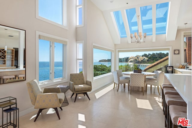 sunroom with a wealth of natural light, vaulted ceiling, a water view, and an inviting chandelier