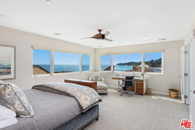 bedroom featuring light carpet, a water view, and ceiling fan