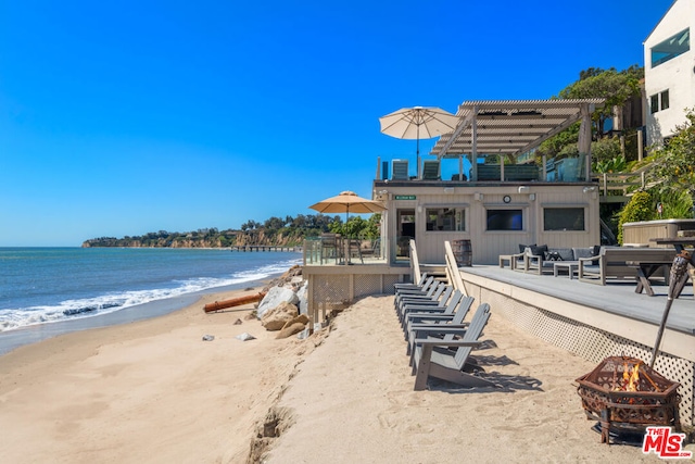 view of water feature featuring an outdoor fire pit and a view of the beach