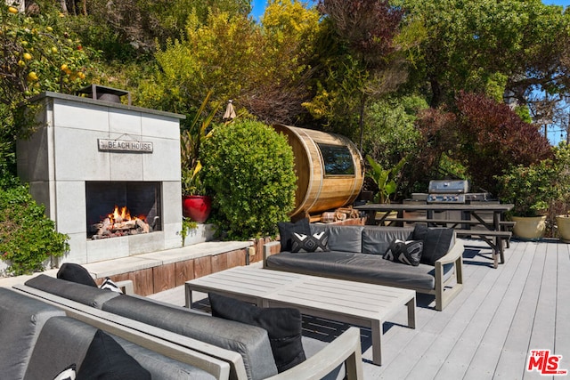 wooden deck featuring a tiled fireplace and grilling area