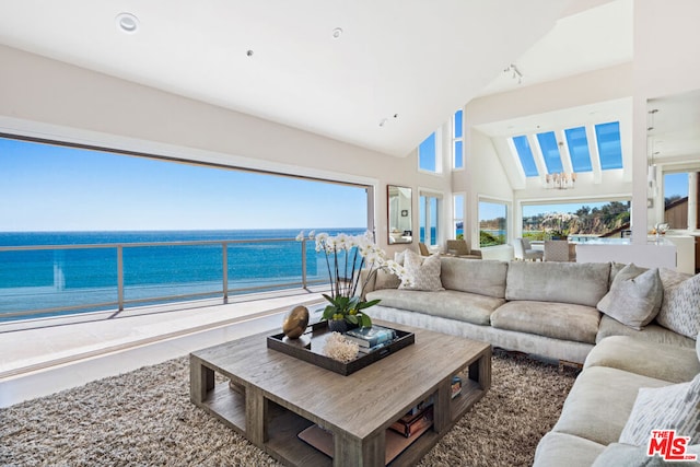 living room with a chandelier, high vaulted ceiling, and a water view