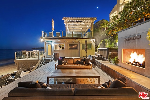 back house at night with a deck with water view and an outdoor living space