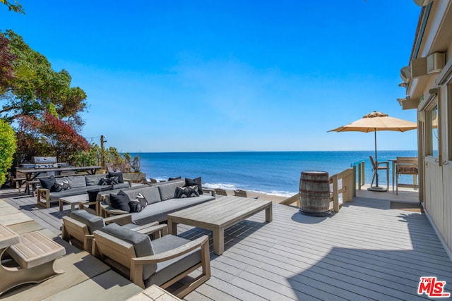 wooden deck featuring an outdoor hangout area, a water view, and a beach view