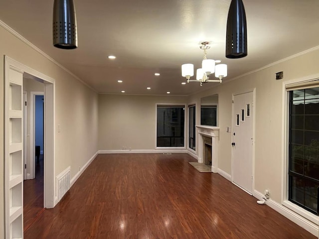 unfurnished living room with dark wood-type flooring, a notable chandelier, and ornamental molding