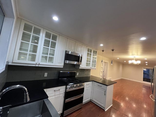 kitchen with white cabinets, appliances with stainless steel finishes, tasteful backsplash, sink, and a chandelier