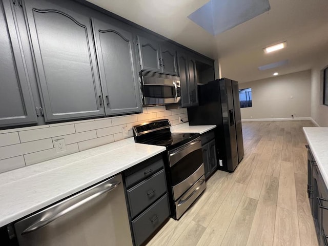 kitchen featuring stainless steel appliances, light hardwood / wood-style floors, and tasteful backsplash