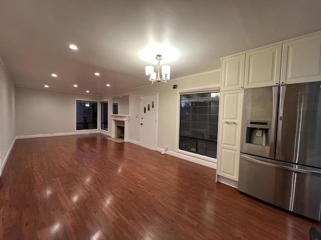 unfurnished living room with crown molding, dark wood-type flooring, and a notable chandelier