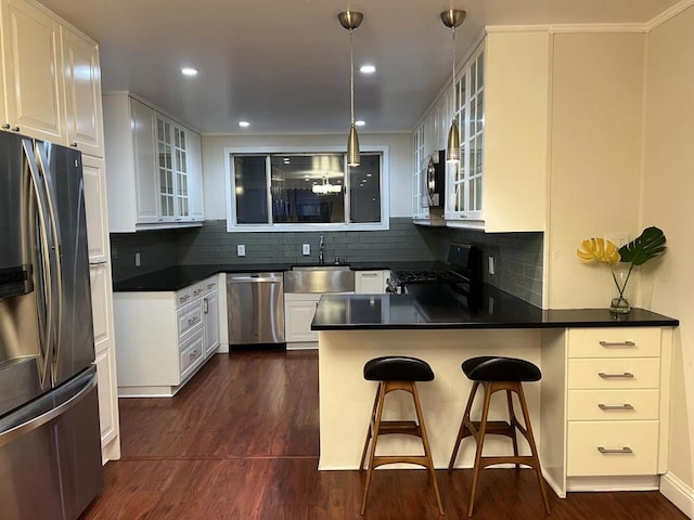 kitchen with kitchen peninsula, sink, white cabinets, a breakfast bar, and stainless steel appliances