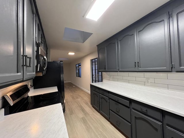 kitchen featuring backsplash, stove, and light wood-type flooring