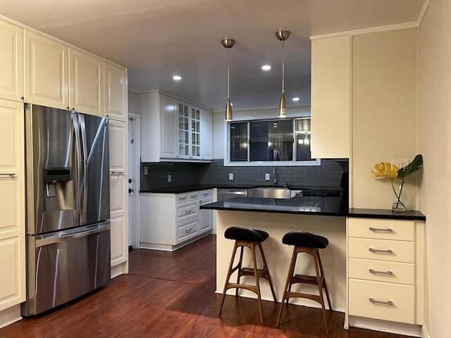 kitchen featuring stainless steel fridge with ice dispenser, kitchen peninsula, white cabinetry, and a kitchen bar