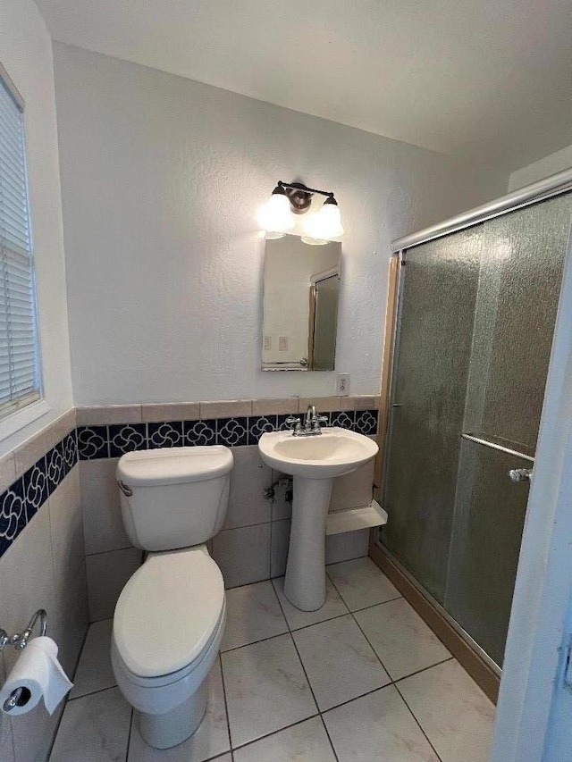 bathroom with toilet, walk in shower, tile walls, sink, and tile patterned floors