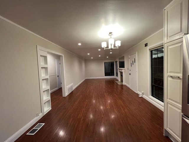 empty room with dark hardwood / wood-style flooring, ornamental molding, and a notable chandelier