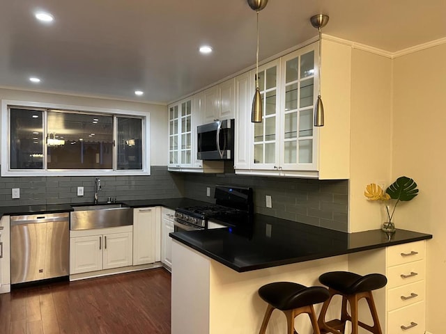 kitchen featuring appliances with stainless steel finishes, tasteful backsplash, a kitchen breakfast bar, sink, and kitchen peninsula