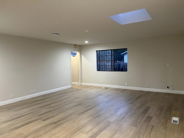 unfurnished room featuring light hardwood / wood-style flooring and a skylight